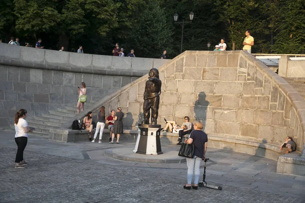 Mensen zitten op de trappen van de dijk in Gorky Park op een zonnige zomerdag met uitzicht op de Krim brug — Stockfoto