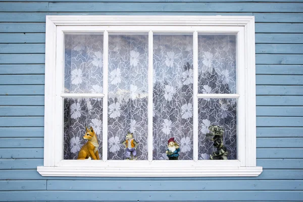 Fenêtres sculptées avec rideaux en tulle et jouets et pots de fleurs sur le rebord de la fenêtre dans le village russe — Photo