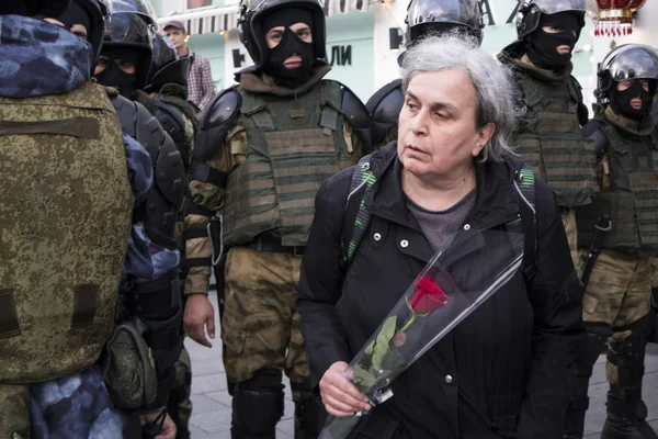 Old woman with the red rose goes ahead of a row of police officers in uniform — Stock Photo, Image