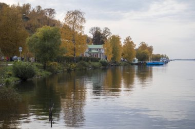 Rusya, Plyos - Ekim 04, 2019: Ivanovo Bölgesi. Volga nehrinin arka planında parlak sarı sonbahar ormanı. Katedral Dağı 'nın yüksekliğinden. Sonbahar güneşli bir günde Varvara kilisesi ve renkli evler.