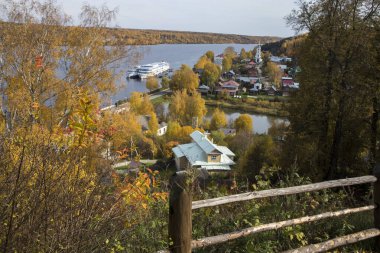Rusya, Plyos - Ekim 04, 2019: Ivanovo Bölgesi. Volga nehrinin arka planında parlak sarı sonbahar ormanı. Katedral Dağı 'nın yüksekliğinden. Sonbahar güneşli bir günde Varvara kilisesi ve renkli evler.