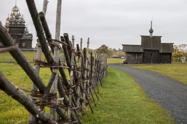 Karelen, Ryssland - 27 augusti 2019: Solnedgång landskap med utsikt över Transfiguration Church och bondgård hus på ön Kizhi, Karelen regionen, Ryssland i regnet — Stockfoto