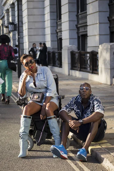 Ragazza in camicia di jeans e una gonna di pelle corta si siede su una sedia a rotelle — Foto Stock