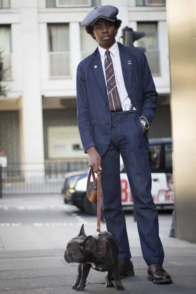 LONDRES, Reino Unido 13 DE SEPTIEMBRE DE 2019: La gente en la calle durante la Semana de la Moda de Londres. Un hombre con gorra y un traje clásico con un bulldog en sus brazos — Foto de Stock