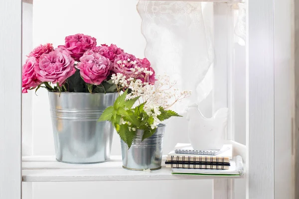 Bouquet of red roses in a tin bucket on a white wall background. Dandelions spring plants in a bucket. Lace curtain Copy space