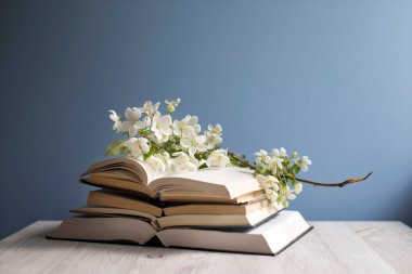 Çiçek açan bir elma ağacının dalı ya da açık bir kitap üzerinde kiraz ağacı ve mavi bir duvarın arka planında bir fincan kahve. Kavram - çevrimiçi öğrenme. Uzayı kopyala Eğitim çevrimiçi