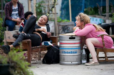 Londra, İngiltere - 17 Temmuz 2019, Göçebe Toplum Bahçesi. Ortak Bahçe Partisi. İki kız bir sokak kafesinde oturuyor. Masa yerine alüminyum fıçı kullanıldı