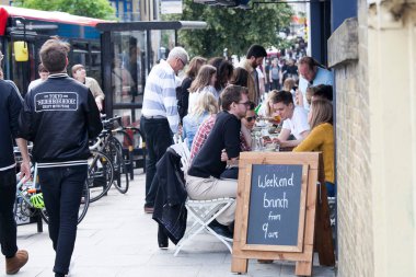 Londra, İngiltere - 17 Temmuz 2019, İnsanlar işlek Brick Lane 'de bir sokak kafesinde oturuyorlar. Siyah tahtaya bir duyuru yazılır - 9 'dan 6' ya kadar brunch