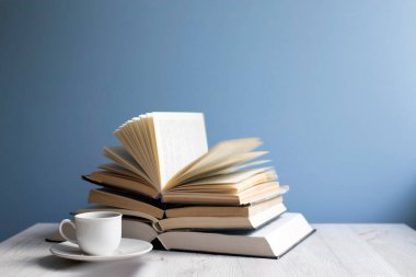 Mavi bir duvarın arkasında açık bir kitap ve bir fincan kahve. Kavram - çevrimiçi öğrenme. Uzayı kopyala Eğitim çevrimiçi