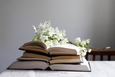 Çiçek açan bir elma ağacının dalı ya da açık bir kitap üzerinde kiraz ağacı ve mavi bir duvarın arka planında bir fincan kahve. Kavram - çevrimiçi öğrenme. Uzayı kopyala Eğitim çevrimiçi