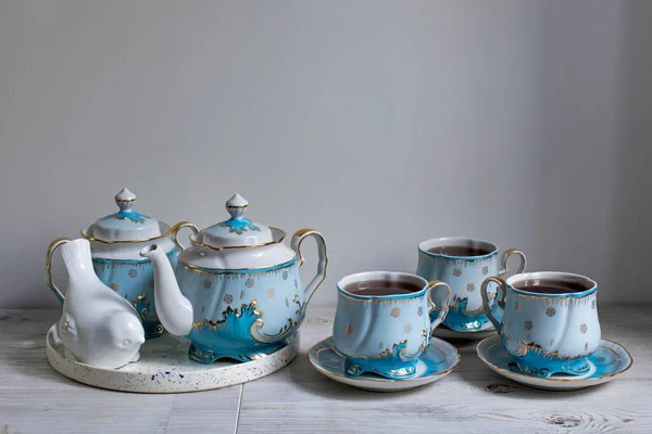 桌上放了一个蓝色瓷茶 茶壶和茶杯 野兔雕像 — 图库照片