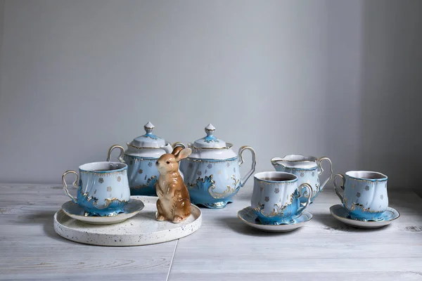 桌上放了一个蓝色瓷茶 茶壶和茶杯 野兔雕像 — 图库照片