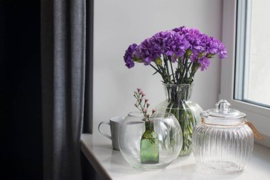 Masa dekorasyonu gibi farklı boyutlarda yuvarlak bir vazoda leylak karanfiller.