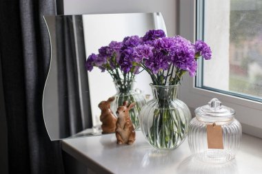 Masa dekorasyonu gibi farklı boyutlarda yuvarlak bir vazoda leylak karanfiller.