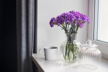 Masa dekorasyonu gibi farklı boyutlarda yuvarlak bir vazoda leylak karanfiller.