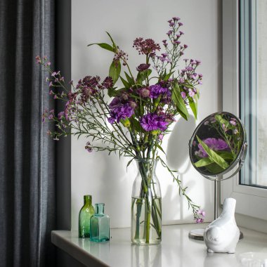 Astrantia güz buketi, mor karanfiller ve iç dekorasyon için pencere eşiğinde bir vazo içinde aster.