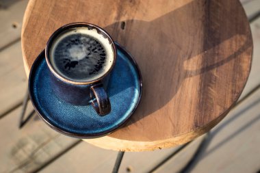 Kahveli seramik mavi fincan sahildeki bir güneş pansiyonunun yanındaki küçük bir masada.