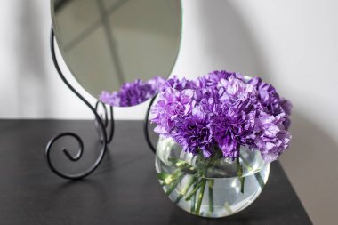 Masa dekorasyonu için cam bir vazoda leylak karanfiller.