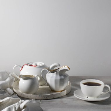 Beyaz arka plandaki masada beyaz seramik çay seti.