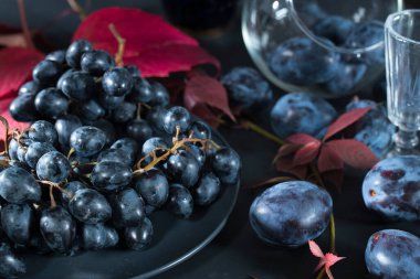 Mavi üzümler, siyah erikler ve kırmızı üzüm yaprakları.