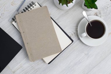 Ofis masası iş yeri, defter, yapay bitki ve fotokopi alanı olan kahve fincanı..