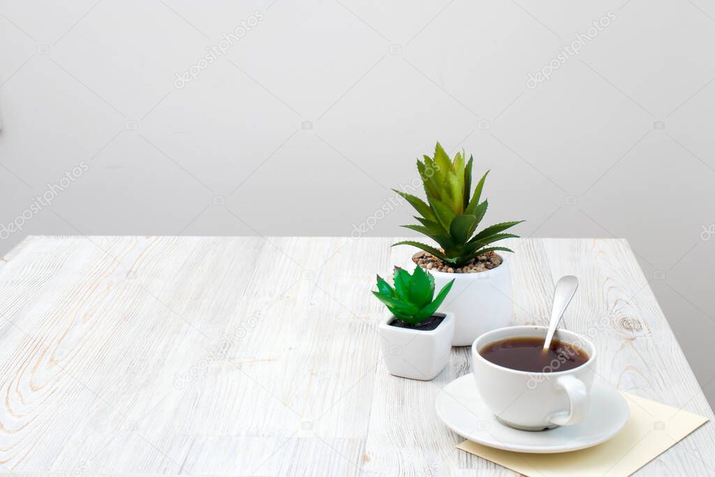 Office desk wood table of Business work place, artificial plants and coffee cup with copy space on grey wooden table.