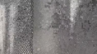 Artificial waterfall. Water flows over a metal mesh in the sunlight