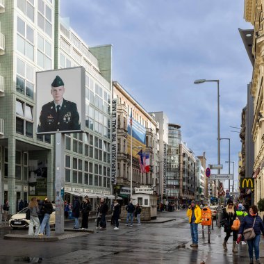 Berlin, Almanya, 5 Mayıs 2025, Berlin, Almanya 'daki Tarihi Kontrol Noktası Charlie, Mauermuseum ve bulutlu bir günde turist ve yerel halkla dolu bir asker portresi