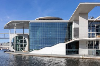 Berlin, Almanya, 5 Mayıs 2025, Marie-Elisabeth-Lueders-Haus ve Paul-Loewe-Haus, Spree Nehri üzerindeki yaya köprüsü ile birbirine bağlı Bundestag binaları. Turist teknesi parlak, güneşli bir günde süzülürken ziyaretçiler nehir kıyısının keyfini çıkarıyorlar.,