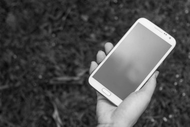 Akıllı bir telefon kullanarak kadın elinin yakın plan çekimi, yeşil doğa geçmişi