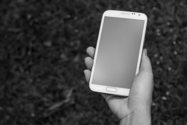 Akıllı bir telefon kullanarak kadın elinin yakın plan çekimi, yeşil doğa geçmişi