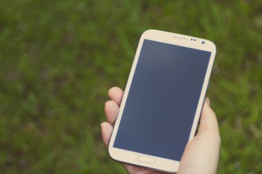 Akıllı telefon kullanan kadın elleri, yeşil doğa geçmişi