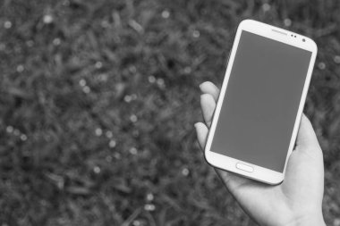 Akıllı bir telefon kullanarak kadın elinin yakın plan çekimi, yeşil doğa geçmişi