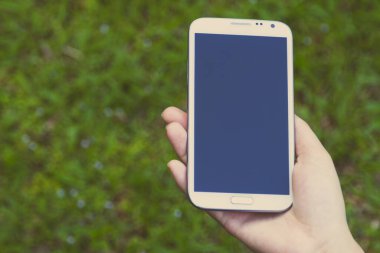 Akıllı telefon kullanan kadın elleri, yeşil doğa geçmişi