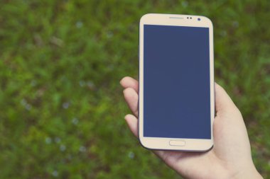 Akıllı telefon kullanan kadın elleri, yeşil doğa geçmişi