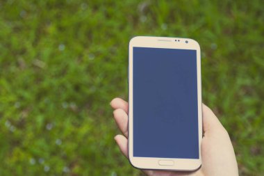 Akıllı telefon kullanan kadın elleri, yeşil doğa geçmişi