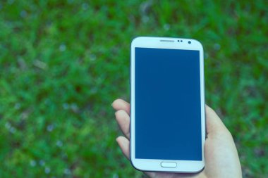 Akıllı telefon kullanan kadın elleri, yeşil doğa geçmişi