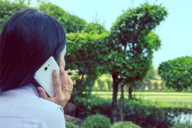 Akıllı bir telefon kullanarak kadın elinin yakın plan çekimi, yeşil doğa geçmişi