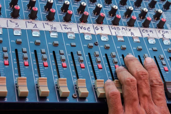 Audio mixing console closeup with hand
