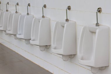 Erkekler tuvaletinde beyaz pisuarlar.