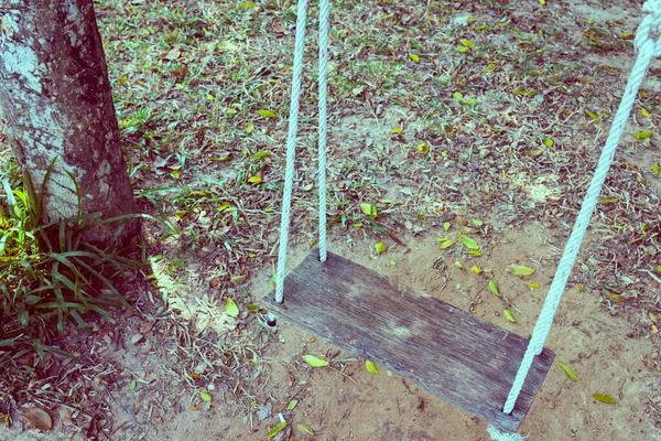 乾燥した葉の背景を持つ古い木のスイング — ストック写真