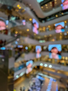 Hareketli bir alışveriş merkezinin bulanık görüntüsü modern bir perakende satış ortamının canlı atmosferini yakalıyor. İnsanlar alışveriş yaparken görülüyor.