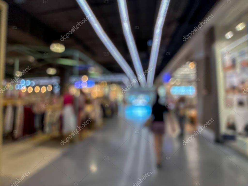 Blurred image of a bustling shopping mall, capturing the vibrant atmosphere of a modern retail environment. People are seen walking, shopping, and enjoying