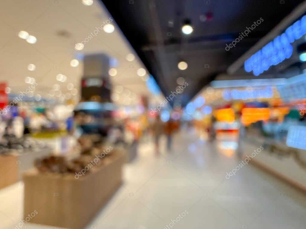 Blurred image of a shopping mall aisle, showcasing the vibrant atmosphere of a modern retail environment. People are seen walking and browsing through various stores