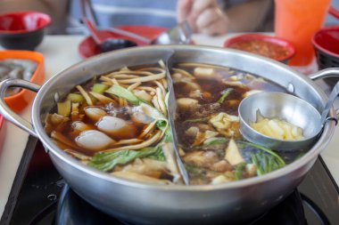 İçi sebze, erişte ve et gibi çeşitli malzemelerle dolu kaynayan sıcak bir tencere. Buhar davetkar bir şekilde yükselir, sıcak ve rahatlatıcı bir atmosfer yaratır..