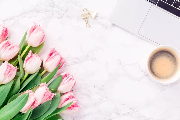 Pink tulips with festive stationary and coffee on white marble background. Feminine job, gender equality, home office and career concept. Copy space Top view. Horizontal