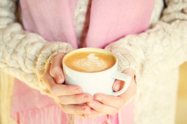 Bir fincan kahve ya da sıcak çikolata ya da chai çay latte tutan kız. Sessiz hygge zaman kavramı. Sıcak sesi. Yatay
