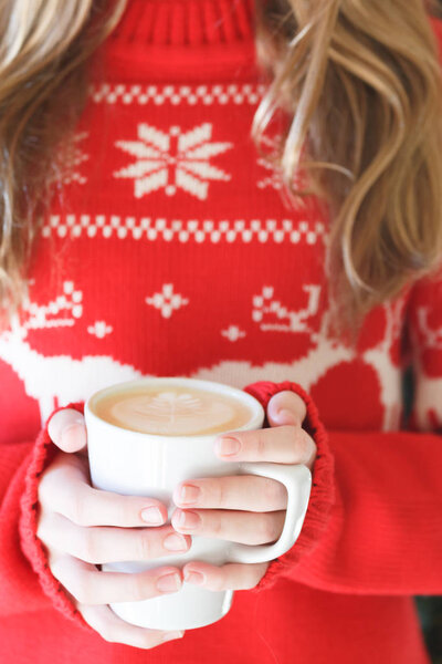 Girl holding a cappuccino cup. Concept of Christmas holiday. Holiday background. Warm tone. Vertical