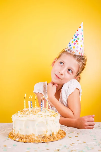 Girl making a wish by birthday cake. Birthday party celebration concept. Vertical
