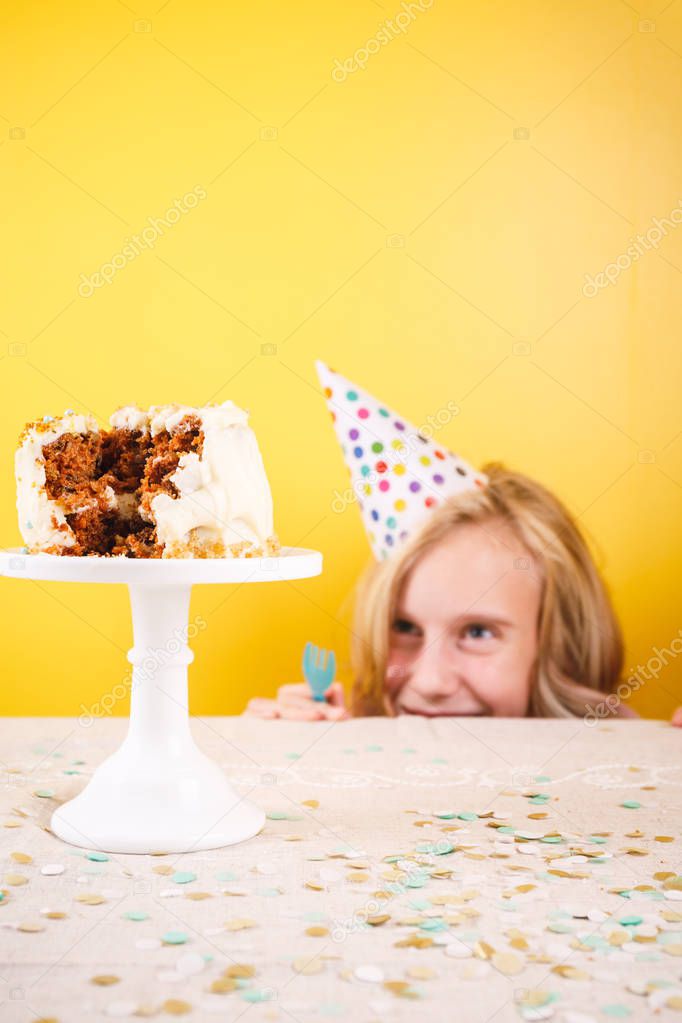 Teenage girl enjoying herself after ruining birthday cake. One person party. Concept of birthday party, messthetics and misconduct. Vertical
